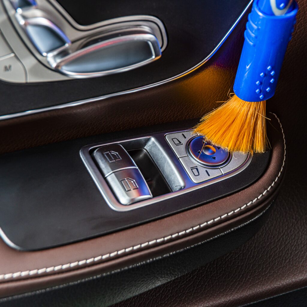 A man cleaning car interior panels and dashboard with yellow microfiber cloth