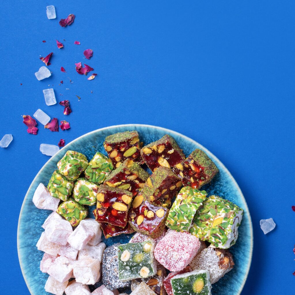 Middle Eastern sweets on blue background. Arab dessert, baklava, halva, rahat lokum, sherbet, nuts, pistachios, dates, raisins, dried apricots, churchkhela, cookies. Top view. Flat lay. Copy space.