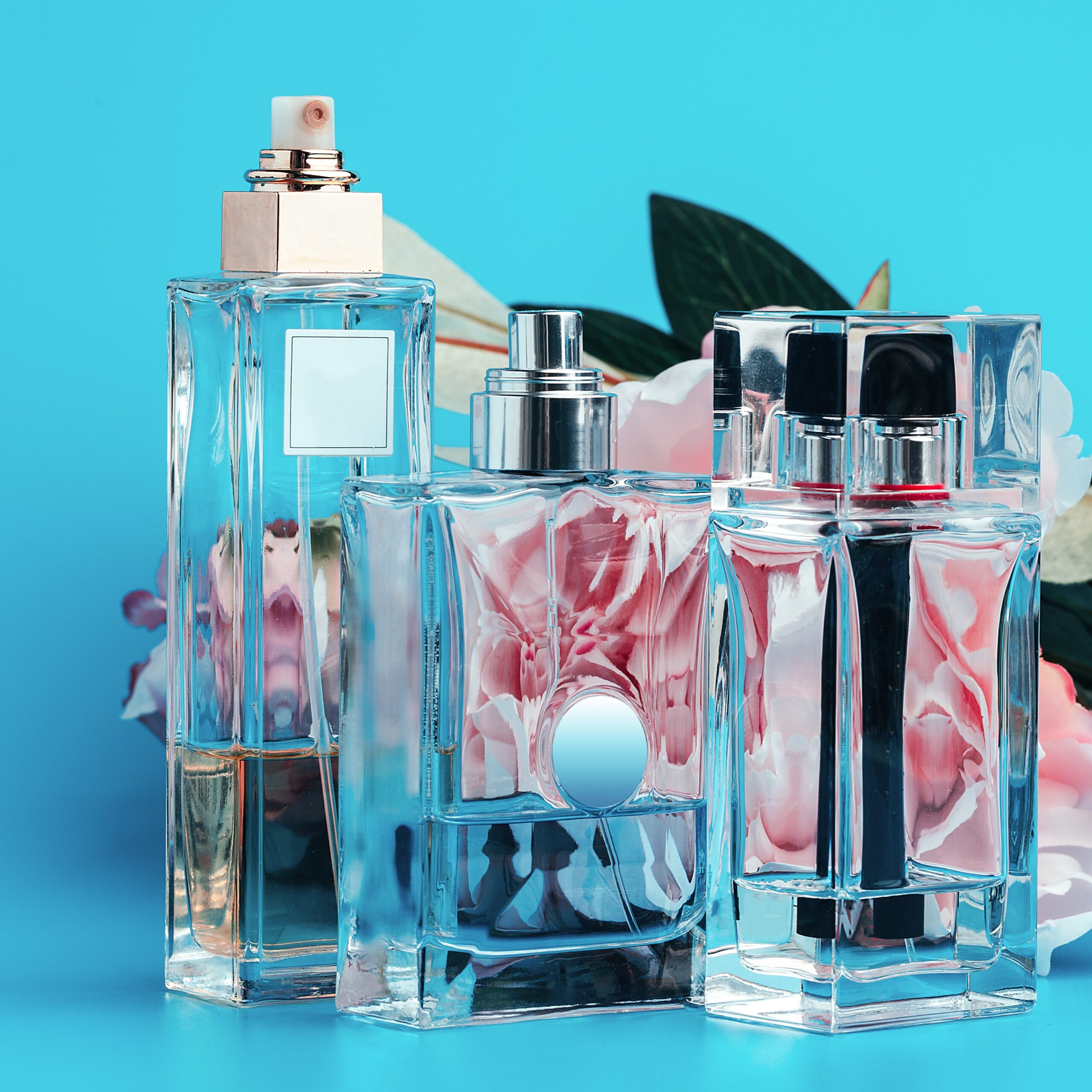 Perfume bottles with flowers on a light blue background. creative photo.